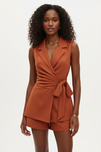 Ensemble 2 pièces blazer sans manches terracotta avec col V à revers sophistiqué, ceinture nouée sculpturale et short assorti - vue de face complète sur fond blanc studio montrant la silhouette allongeante et chic, le tissu 100% polyester en terracotta chaleureux et tendance - Mannequin en pose confiante et professionnelle - Collection mode féminine accessible premium Black-Coat