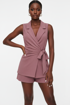 Ensemble 2 pièces blazer sans manches rose poudré avec col V à revers sophistiqué, ceinture nouée sculpturale et short assorti - vue de face complète sur fond blanc studio montrant la silhouette allongeante et chic, le tissu 100% polyester en rose poudré doux et féminin - Mannequin en pose confiante et professionnelle - Collection mode féminine accessible premium Black-Coat