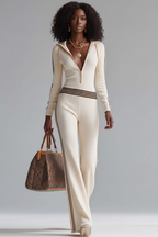 Ensemble sportswear côtelé Black-Coat beige avec zip et bandes latérales - vue trois-quarts dynamique d'une mannequin en pose confiante sur fond blanc studio, mettant en valeur le haut à capuche avec zip, la maille côtelée douce, les bandes latérales contrastées et le pantalon à jambes larges moderne