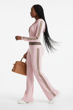 Ensemble sportswear côtelé Black-Coat rose avec zip et bandes latérales - profil latéral complet d'une mannequin en mouvement gracieux sur fond blanc studio, soulignant la silhouette sculptée par la maille côtelée, les bandes latérales visibles de profil, le zip frontal et le style athleisure chic