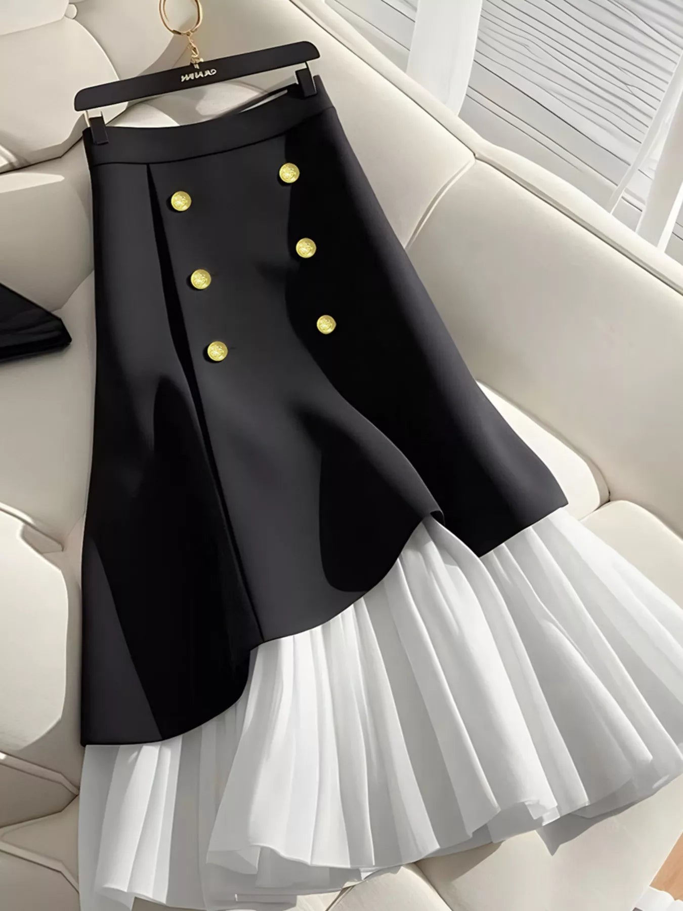 "Jupe plissée noire taille haute avec détails boutonnés - vue de face montrant les plis élégants et la structure architecturale BLACK-COAT"