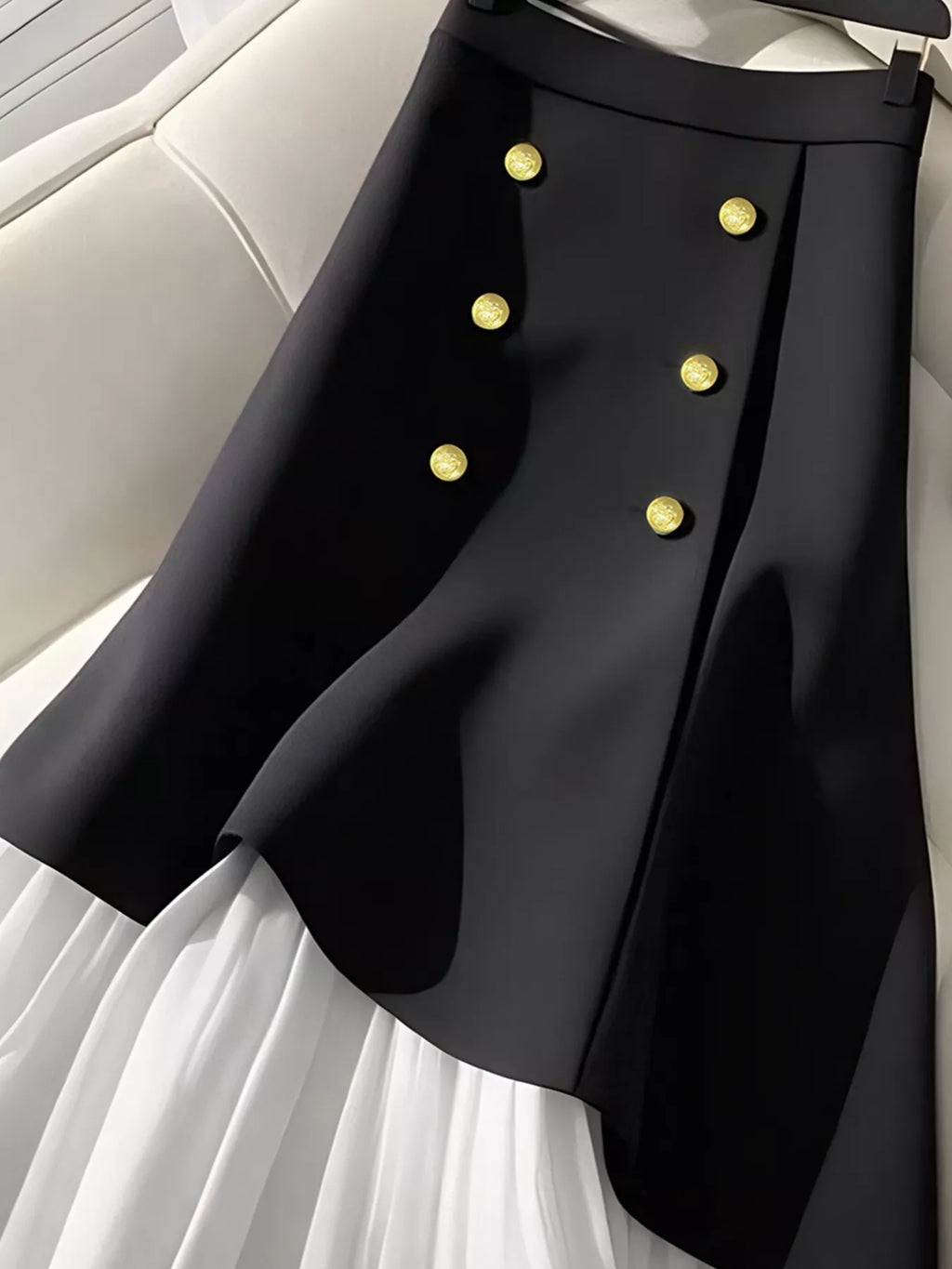 Détail de la taille haute et des boutons décoratifs - jupe plissée BLACK-COAT alliant sophistication et finitions soignées"