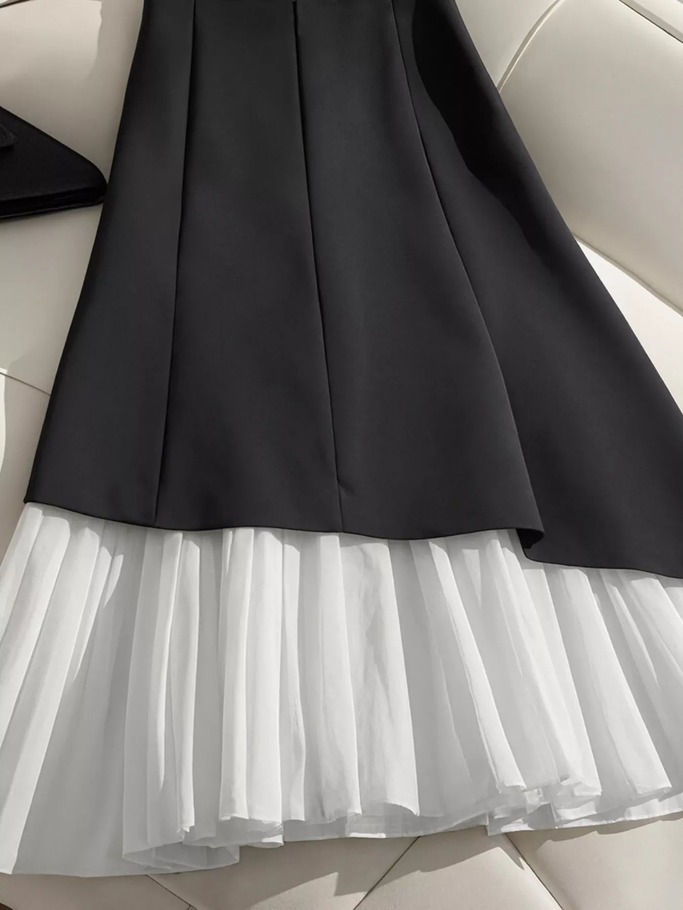 "Jupe noire plissée BLACK-COAT - vue arrière illustrant la coupe structurée et l'élégance intemporelle du design"