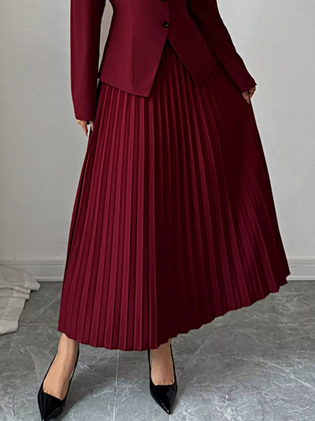 Jupe midi plissée élégante, plis permanents structurés, longueur midi flatteuse, taille haute, vue de face montrant les plis verticaux sophistiqués
