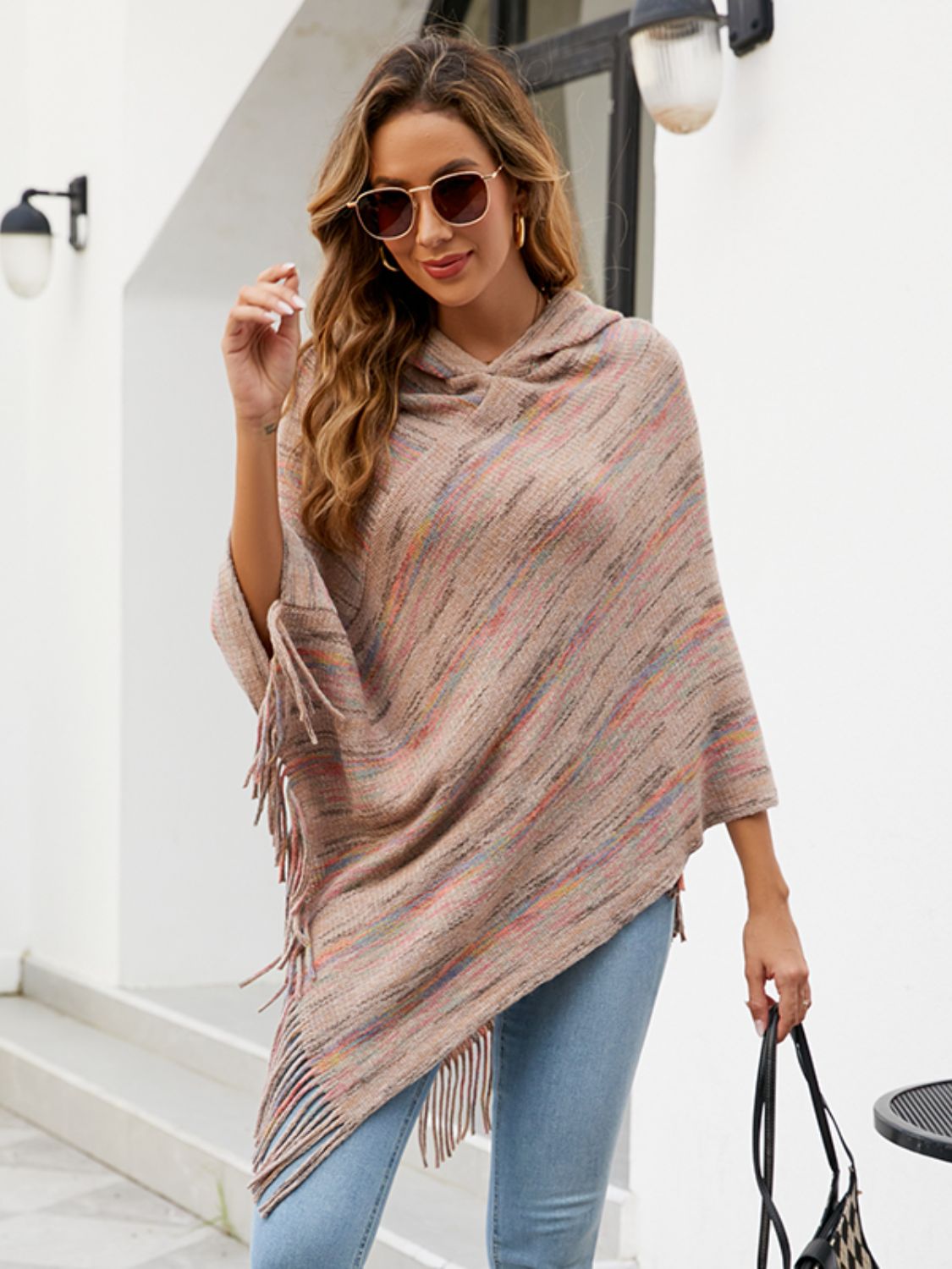 Vue latérale profil poncho à capuche avec franges, silhouette ample tombante, capuche visible de côté, franges longues au bas, tissu tricoté ou tissé chaleureux
