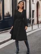Détail col noué de la robe asymétrique BLACK-COAT - gros plan sur le nœud architectural unique, montrant la qualité du tissu opaque, la finition soignée des boutons et le design contemporain qui attire le regard
