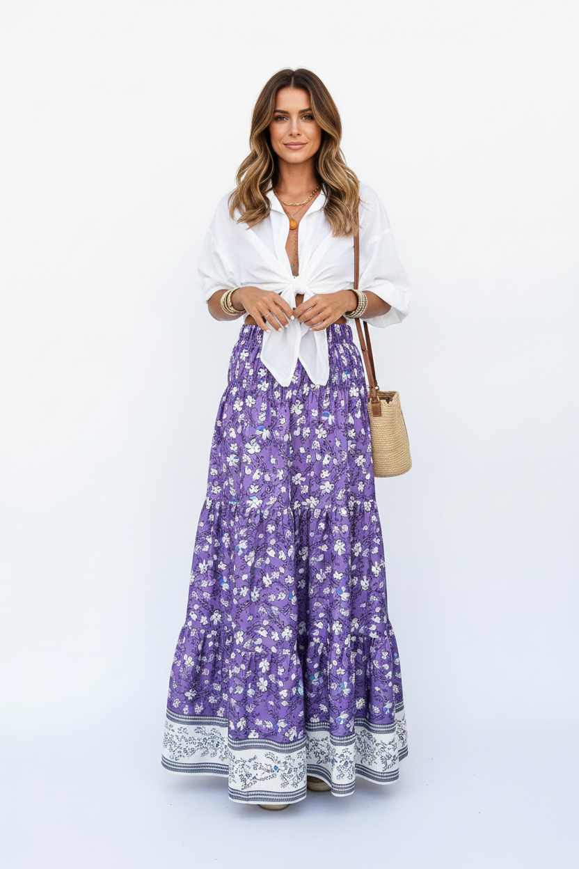 Jupe longue bohème Black-Coat violette à imprimé floral avec volants étagés et bordure contrastée - vue de face frontale complète d'une mannequin en pose debout sur fond blanc studio, présentant la taille élastique confortable, les trois étages de volants superposés, l'imprimé floral violet et blanc délicat, la bordure décorative en bas et la longueur maxi fluide et bohème