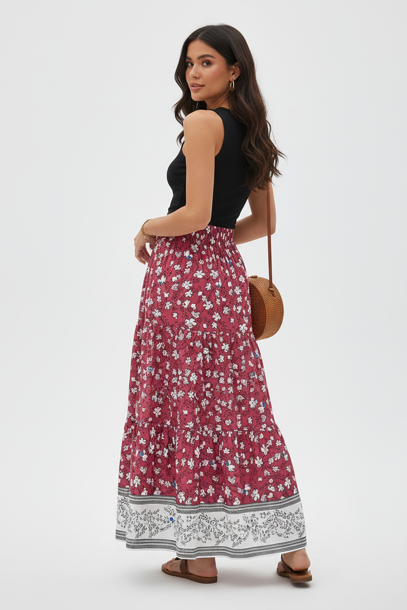 Jupe longue bohème Black-Coat à imprimé floral avec volants étagés et bordure contrastée - vue arrière trois-quarts d'une mannequin en rotation douce sur fond blanc studio, dévoilant les détails de construction des volants étagés vus de côté, le mouvement fluide de la jupe maxi et la bordure décorative qui encadre le bas de la jupe