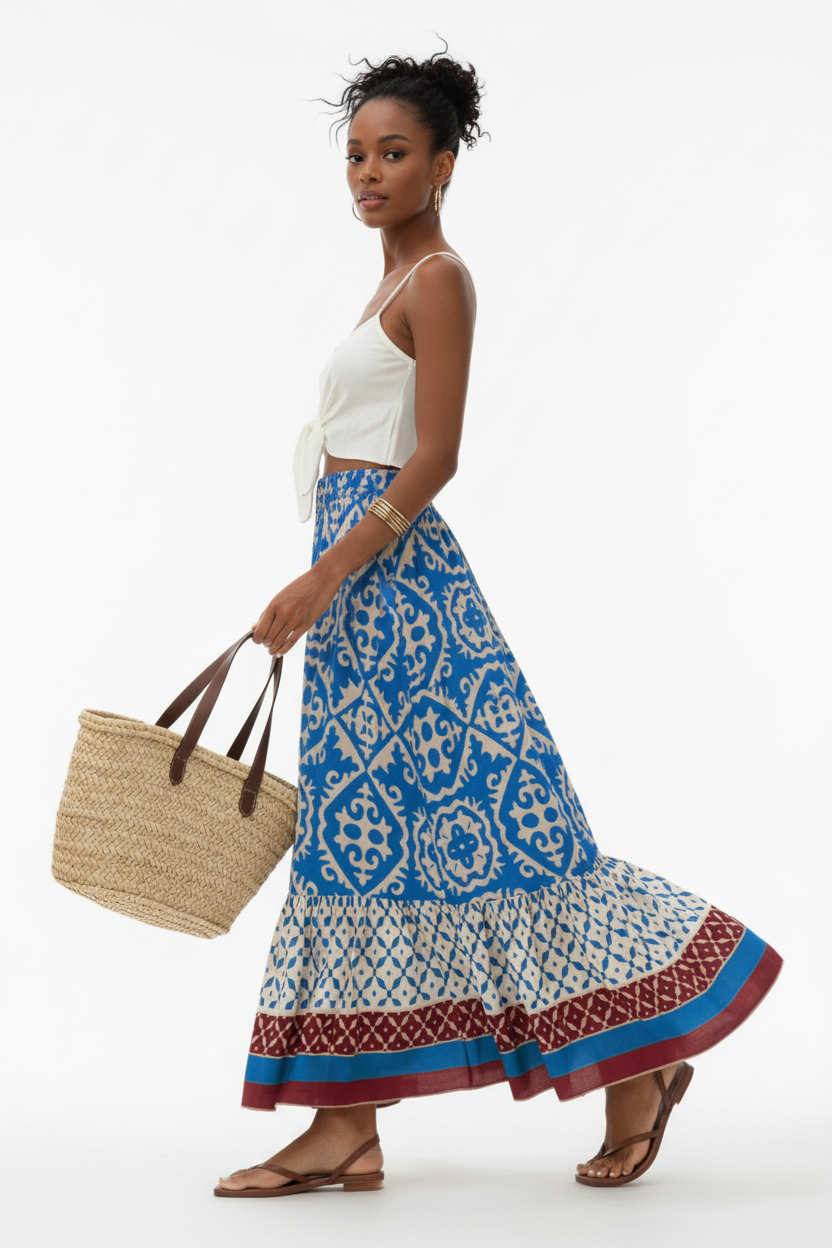 Jupe longue bohème Black-Coat bleue et beige à imprimé géométrique avec volants étagés et bordure contrastée - profil latéral complet d'une mannequin en mouvement gracieux sur fond blanc studio, soulignant le mouvement fluide des volants étagés, la silhouette bohème romantique, l'imprimé géométrique bleu et beige et la bordure décorative qui ajoute une touche artisanale