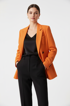 Blazer femme double boutonnage texturé orange veste structurée premium - pose confiante professionnelle montrant la fermeture double boutonnage signature avec boutons noirs, tissu texturé raffiné premium, coupe structurée flatteuse, doublure complète, épaulettes structurées, confiance et élégance intemporelle - BLACK-COAT