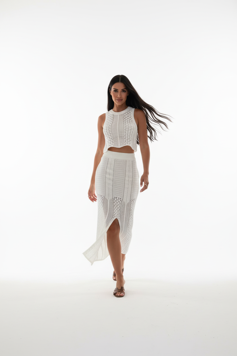 "Ensemble deux pièces crochet blanc - en marche mouvement naturel montrant la jupe midi crochet avec fente centrale qui s'ouvre en marchant, crop top ajusté, silhouette dynamique, texture crochet ajourée, fond blanc studio BLACK-COAT"