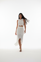 "Ensemble deux pièces crochet blanc - en marche mouvement naturel montrant la jupe midi crochet avec fente centrale qui s'ouvre en marchant, crop top ajusté, silhouette dynamique, texture crochet ajourée, fond blanc studio BLACK-COAT"
