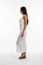  "Ensemble deux pièces crochet blanc - vue de profil latéral montrant la silhouette ajustée du crop top crochet et de la jupe midi, texture tricot ajouré visible, fente latérale de la jupe, fond blanc studio BLACK-COAT"