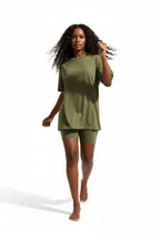 Mannequin en marche dynamique de profil portant l'ensemble coordonné t-shirt oversize et short cycliste kaki olive Black-Coat, vue latérale — coloris kaki naturel et tendance évoquant l'aventure et la liberté, t-shirt oversize au tombé décontracté visible de profil, manches courtes légères, short cycliste gainant dévoilant la jambe avec élégance, silhouette sportive et moderne capturée en mouvement, fond blanc, photographie mode éditoriale sporty chic Black-Coat
