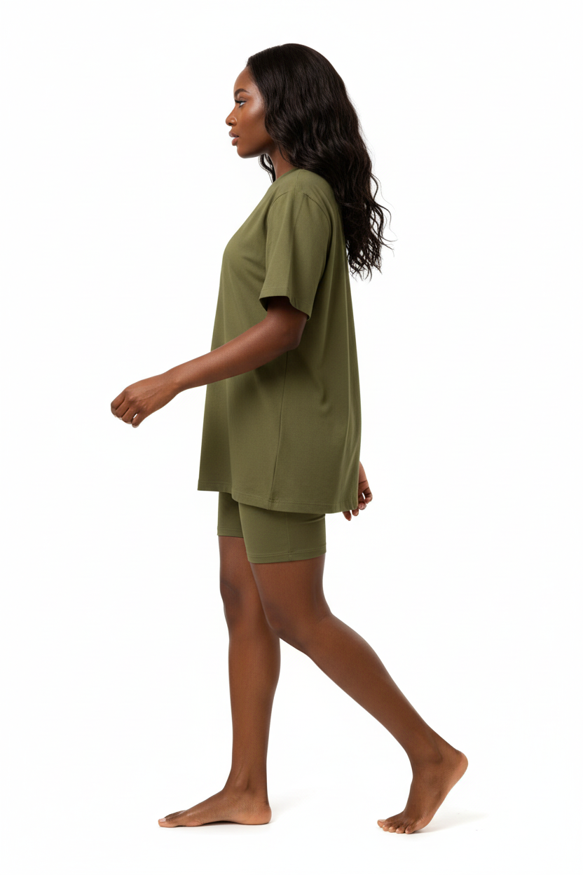  Mannequin en marche dynamique de profil portant l'ensemble coordonné t-shirt oversize et short cycliste kaki olive Black-Coat, vue latérale — coloris kaki naturel et tendance évoquant l'aventure et la liberté, t-shirt oversize au tombé décontracté visible de profil, manches courtes légères, short cycliste gainant dévoilant la jambe avec élégance, silhouette sportive et moderne capturée en mouvement, fond blanc, photographie mode éditoriale sporty chic Black-Coat