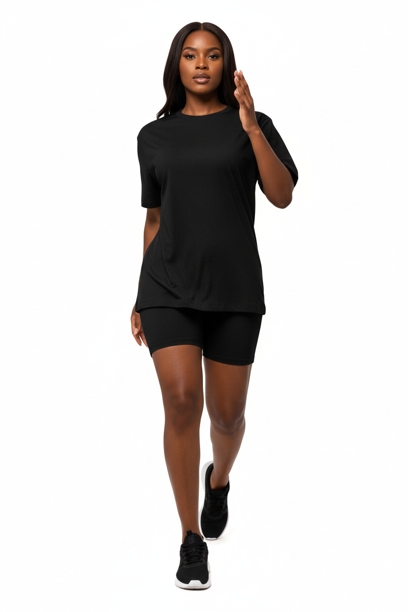  Mannequin en pleine foulée portant l'ensemble coordonné t-shirt oversize et short cycliste noir Black-Coat, vue en contre-plongée dynamique — effet de puissance et d'assurance absolue, silhouette allongée et magnifiée par l'angle dramatique, t-shirt oversize col rond au tombé parfait, manches courtes structurées, short cycliste gainant et confortable, coloris noir intemporel et indémodable sublimant chaque silhouette, fond blanc immaculé, éclairage naturel dramatique, photographie mode éditoriale Black-Coa