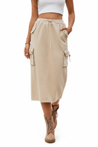 Jupe cargo beige mi-longue avec multiples poches latérales - pose en mouvement de face illustrant le confort et la praticité du vêtement - BLACK-COAT