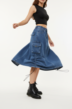  Jupe cargo en jean bleu mi-longue avec poches latérales - pose en rotation montrant le mouvement fluide du tissu denim et l'amplitude de la jupe - BLACK-COAT