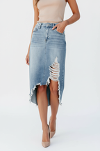 Vue trois-quarts en marche : "Jupe midi en jean délavé bleu clair avec détails effilochés - vue de profil trois-quarts montrant le mannequin en marche avec silhouette fluide et finitions brutes - BLACK-COAT"