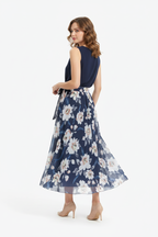 Jupe maxi imprimé floral bleu foncé avec ceinture à nouer - vue arrière trois-quarts avec mannequin regardant par-dessus l'épaule montrant détail ceinture nouée tissu floral fluide et drapé élégant de la jupe maxi - BLACK-COAT