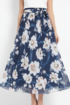 Jupe maxi imprimé floral bleu foncé avec ceinture à nouer - gros plan de la taille aux cuisses montrant détails de la ceinture ajustable à nouer motif floral blanc romantique sur fond bleu foncé et tissu polyester fluide avec mannequin en léger mouvement - BLACK-COAT