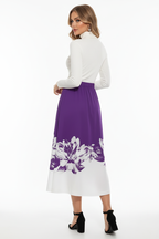 Jupe midi ligne A imprimé floral violette - vue arrière trois-quarts avec mannequin regardant par-dessus l'épaule montrant silhouette A-line bordure florale blanche et drapé élégant de la jupe midi - BLACK-COAT