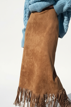 Jupe midi velours camel avec franges - gros plan détail montrant l'ourlet à franges décoratives marron, texture velours camel riche et douce visible en détail, finition artisanale des franges, qualité premium, fond blanc studio BLACK-COAT