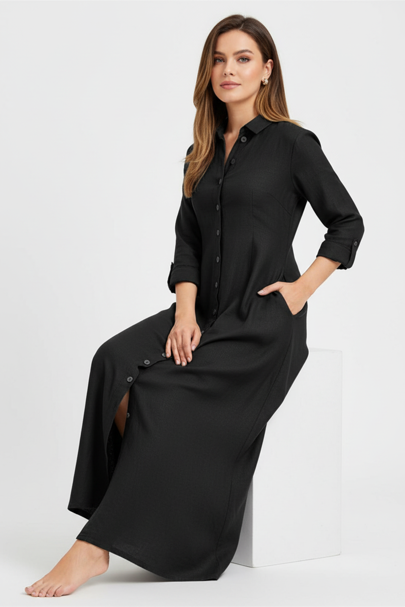 Robe chemise noire longue avec boutonnage frontal et poches latérales - pose assise démontrant le tombé fluide du tissu et le confort d'utilisation - BLACK-COAT