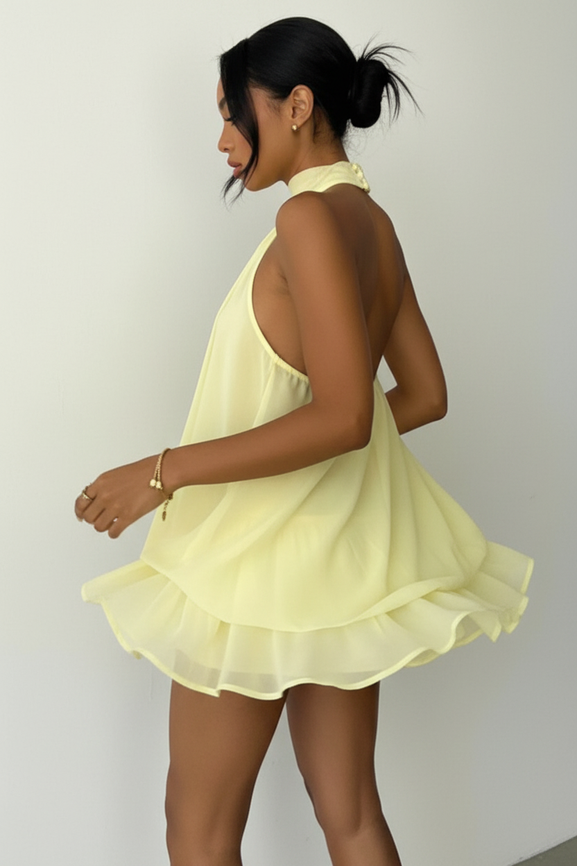 Robe mini halter Black-Coat à volants superposés - vue arrière trois-quarts d'une mannequin en rotation douce sur fond blanc studio, dévoilant les détails de construction de la jupe à double volant, le dos nu élégant avec attache au cou et le mouvement fluide du tissu polyester de qualité premium