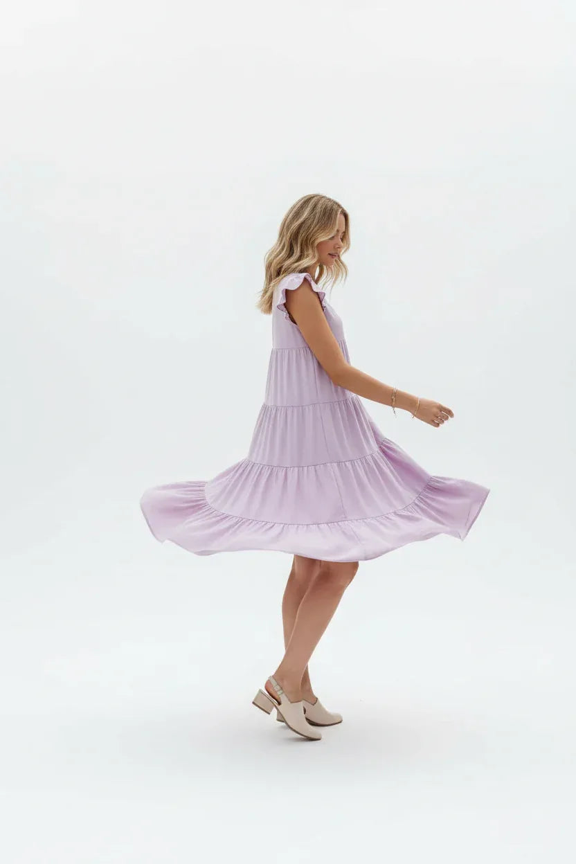 "Robe à volants étagés lilas avec manches papillon - vue trois-quarts en mouvement tournant montrant le flux des volants et la coupe évasée - BLACK-COAT"