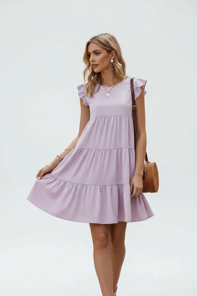 Robe à volants étagés lilas avec manches papillon - vue de face montrant le mannequin en marche avec construction à quatre niveaux et silhouette fluide - BLACK-COAT"