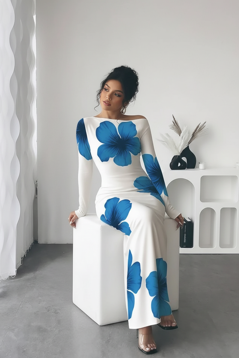 "Robe maxi blanche imprimé floral bleu épaule asymétrique - vue assise montrant le drapé naturel de la robe en position assise, confort et élégance, décolleté asymétrique, imprimé floral bleu vibrant, mannequin sur cube blanc, fond blanc studio BLACK-COAT"
