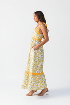 Robe maxi blanche imprimé floral jaune vue de profil montrant la silhouette complète, les volants étagés, les détails crochet et le style bohème romantique - BLACK-COAT