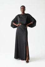 Mannequin portant la Robe Maxi Manches Chauve-Souris Black-Coat noire - vue de face montrant l'encolure bateau et les manches chauve-souris dramatiques