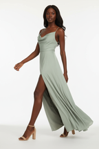 Détail de la fente latérale de la robe maxi satin vert sauge Black-Coat - mannequin noire en mouvement révélant la jambe à travers la fente élégante et le tombé fluide du satin premium accessible

