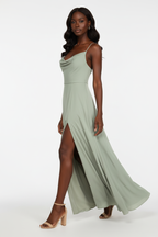 Robe maxi cowl neck satin vert sauge Black-Coat - vue trois-quarts avec mannequin  en marche montrant la jambe à travers la fente et le mouvement gracieux du tissu, vêtement élégant tendance abordable
