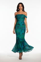 "Robe sirène maxi émeraude épaules dénudées froncée - en marche mouvement naturel montrant la robe portée en mouvement, ourlet sirène évasé qui bouge élégamment, silhouette dynamique glamour, motif vert émeraude, fond blanc studio BLACK-COAT"