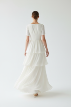  "Robe étagée encolure crantée manches courtes BLACK-COAT - vue de dos montrant mannequin en marche, détail de la construction étagée arrière, fluidité des volants en mouvement et ligne décontractée sur fond blanc studio"