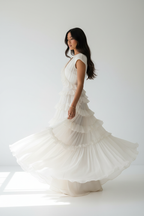 "Robe étagée encolure crantée manches courtes BLACK-COAT - vue trois-quarts latérale montrant mannequin en rotation gracieuse, mouvement des volants étagés, coupe décontractée élégante et tombé fluide du tissu sur fond blanc studio"