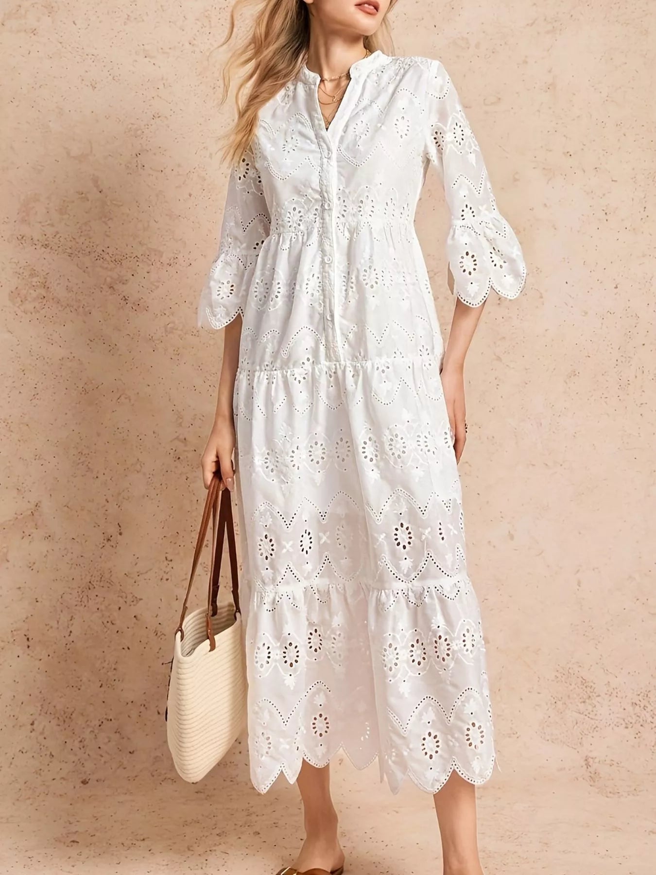 Robe midi étagée en broderie anglaise avec encolure échancrée en V, détails eyelet délicats, décolleté notched en V, volants étagés superposés créant du volume, longueur midi, vue de face montrant la broderie anglaise romantique et les volants étagés
