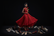 un fond noir avec une femme noir vêtus d'une robe rouge avec une rose a la main des talon rouge et plein de chaussures autour d'elle